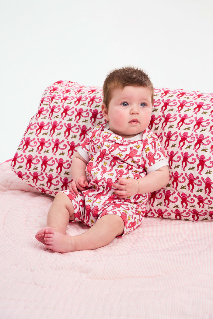 The Roller Rabbit Infant Monkey Short Sleeve Zipper Onesie features playful pink monkeys and yellow bananas on a white background, with white trim for comfort. Made from breathable Pima cotton, it's perfect for infants.