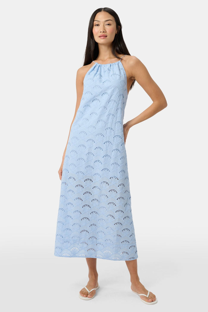 A woman wears the Roller Rabbit Jemina Eyelet Athena Dress, a sky blue, sleeveless cotton sundress with a gathered halter neckline and eyelet details, paired with white sandals, set against a plain white background.