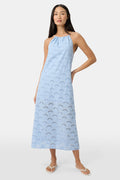 A woman wears the Roller Rabbit Jemina Eyelet Athena Dress, a sky blue, sleeveless cotton sundress with a gathered halter neckline and eyelet details, paired with white sandals, set against a plain white background.