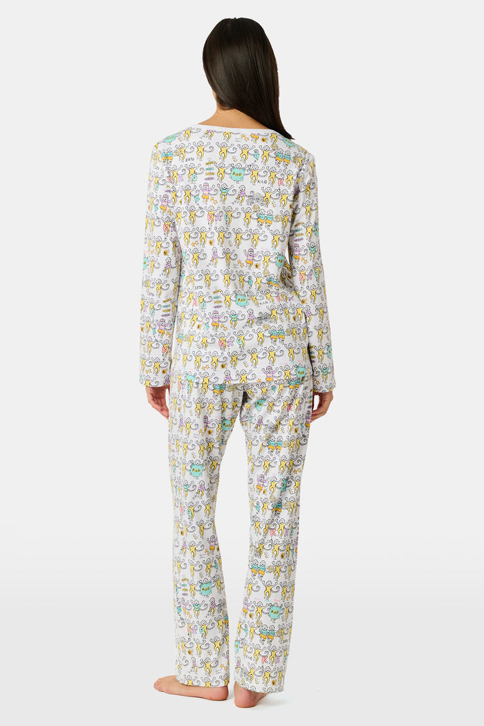 The Roller Rabbit Kappa Alpha Theta Monkey Pajamas set features a white, long-sleeved buttoned top and matching pants, both adorned with a vibrant all-over cartoon print of playful animal characters, including cheerful monkeys.