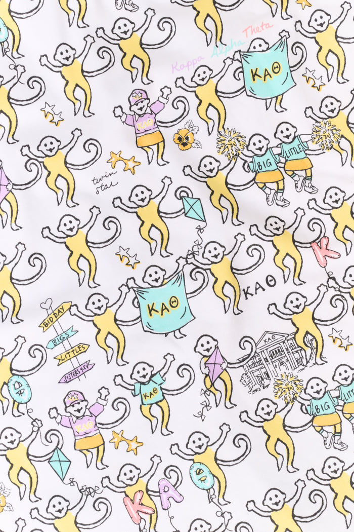 The Kappa Alpha Theta Monkey Polo Pajamas from Roller Rabbit are a short-sleeve button-up set with matching shorts, showcasing a lively print of colorful cartoon monkeys and doodles on a crisp white background. They feature an elastic waistband for comfort and are crafted from soft Pima cotton for a gentle feel.