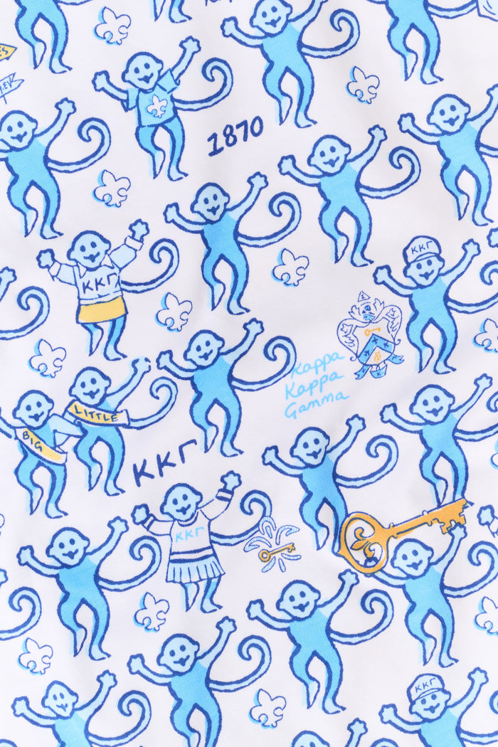 The Roller Rabbit Kappa Kappa Gamma Monkey Polo Pajamas feature a short-sleeve button-up pajama shirt with a front button placket and matching shorts with an elastic waistband, adorned with a playful blue monkey and yellow motif on a white background. Crafted from soft Pima cotton for extra comfort.
