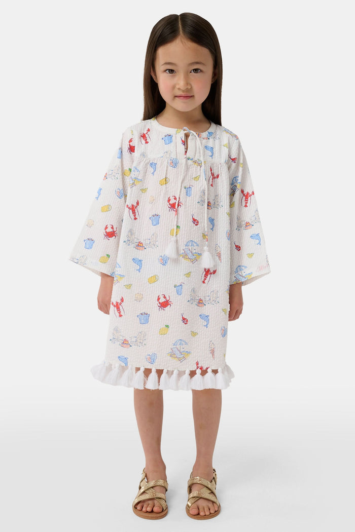 A young child with light brown hair smiles near an open car door, wearing the Roller Rabbit Kids Catch of the Day Serafina Tunic. An adult in matching pajamas is partially visible behind them.