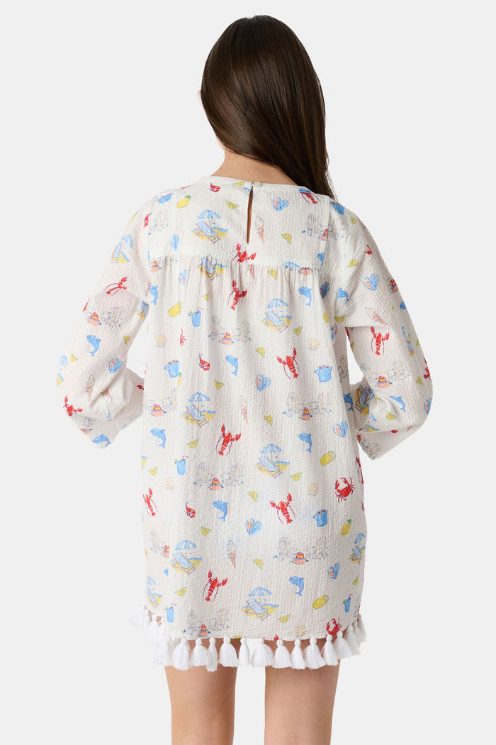 A young child with light brown hair smiles near an open car door, wearing the Roller Rabbit Kids Catch of the Day Serafina Tunic. An adult in matching pajamas is partially visible behind them.