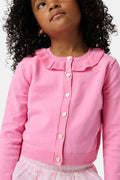 The Kids Ellis Cardigan by Roller Rabbit is a rose pink, long-sleeve cardigan featuring a ruffled collar and pearl-like buttons. Shown flat on a white background, it's made from soft cotton sweater material.