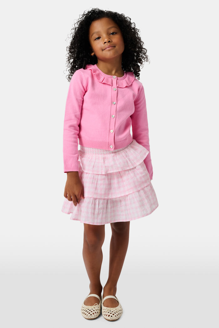 The Kids Ellis Cardigan by Roller Rabbit is a rose pink, long-sleeve cardigan featuring a ruffled collar and pearl-like buttons. Shown flat on a white background, it's made from soft cotton sweater material.