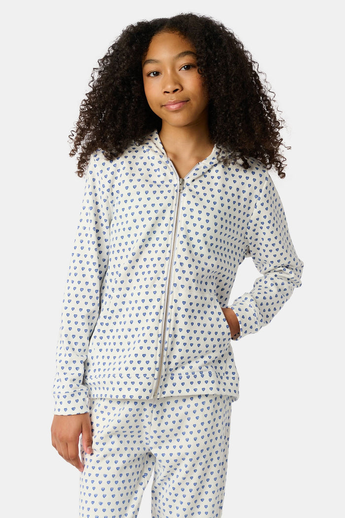 A smiling young child with brown hair wears the Roller Rabbit Kids Hearts Harley Hoodie and matching pants, both made from 100 cotton French terry, standing with hands in the hoodie’s pockets against a plain light background.