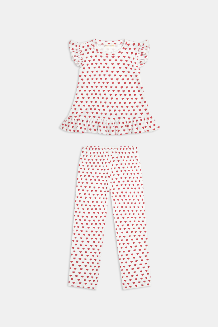 A child with long blonde hair wears the Roller Rabbit Kids Hearts Riley Set made from Pima Waffle fabric, featuring red hearts and ruffled cap sleeves, while holding a notebook with a decorative cover and standing in front of lockers.