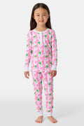 A young girl smiles barefoot against a white background in Roller Rabbit's Kids Leo The Lion Pajamas—soft Pima cotton, long sleeves, white cuffs, and a playful pink-and-green animal print.