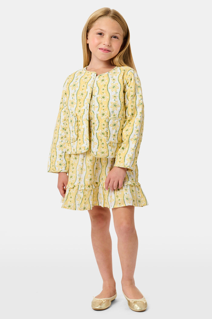 A young girl wearing a Roller Rabbit Kids Lillian Floral Stripe Finn Jacket paired with a matching ruffled skirt and gold ballet flats, standing and smiling against a plain white background—perfect for back-to-school style.