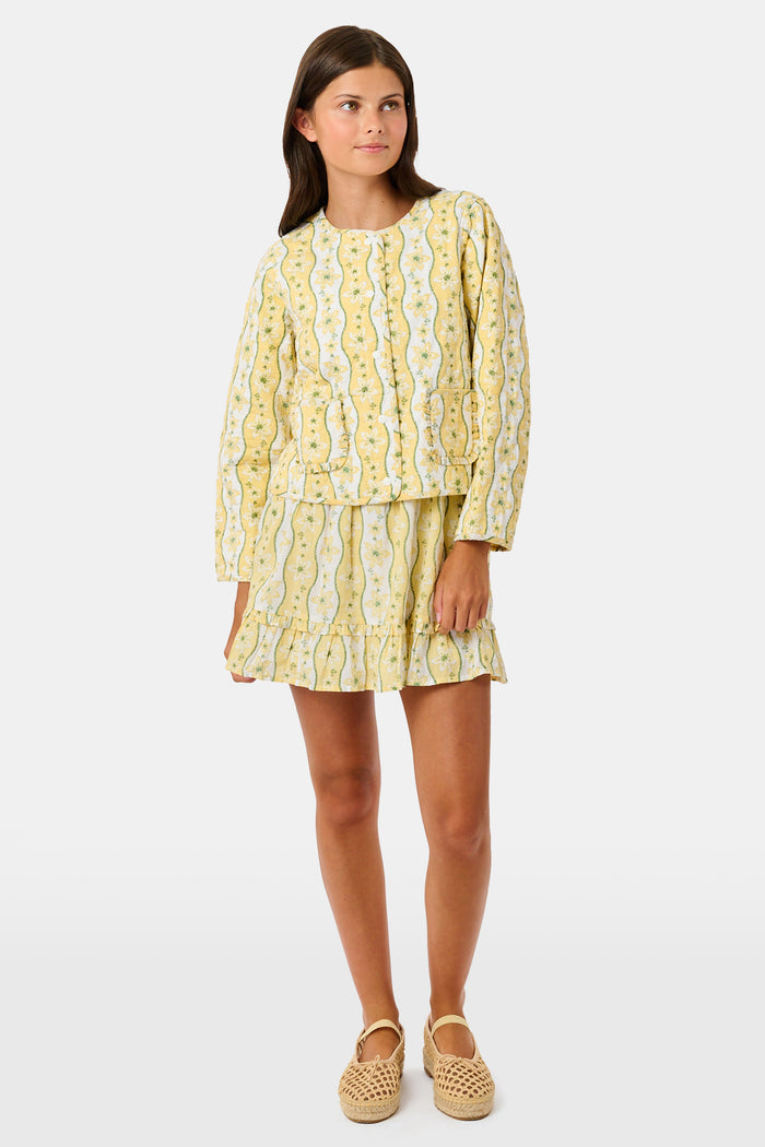 A young girl wearing a Roller Rabbit Kids Lillian Floral Stripe Finn Jacket paired with a matching ruffled skirt and gold ballet flats, standing and smiling against a plain white background—perfect for back-to-school style.