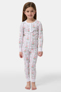 A young girl stands barefoot in Roller Rabbit Kids Monkey Block Stripe Pajamas—matching long-sleeve top and pants with playful monkey block stripes—smiling against a plain light gray background.