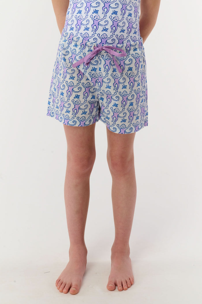 A child models the Roller Rabbit Kids Monkey Lounge Short—a matching pajama set with a blue and purple monkey print, sleeveless top, and cambric shorts with a purple drawstring—against a plain white background.