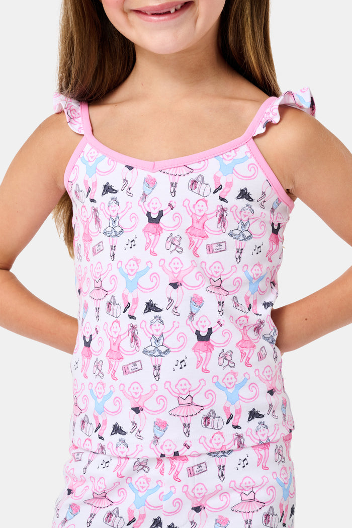 The Kids Monkey Pirouette Blaire Pajamas by Roller Rabbit is a children's pajama set crafted from soft Pima cotton, featuring a sleeveless top with ruffled straps and long pants, both in white with a playful pink, blue, and black monkey cartoon print and pink trim.