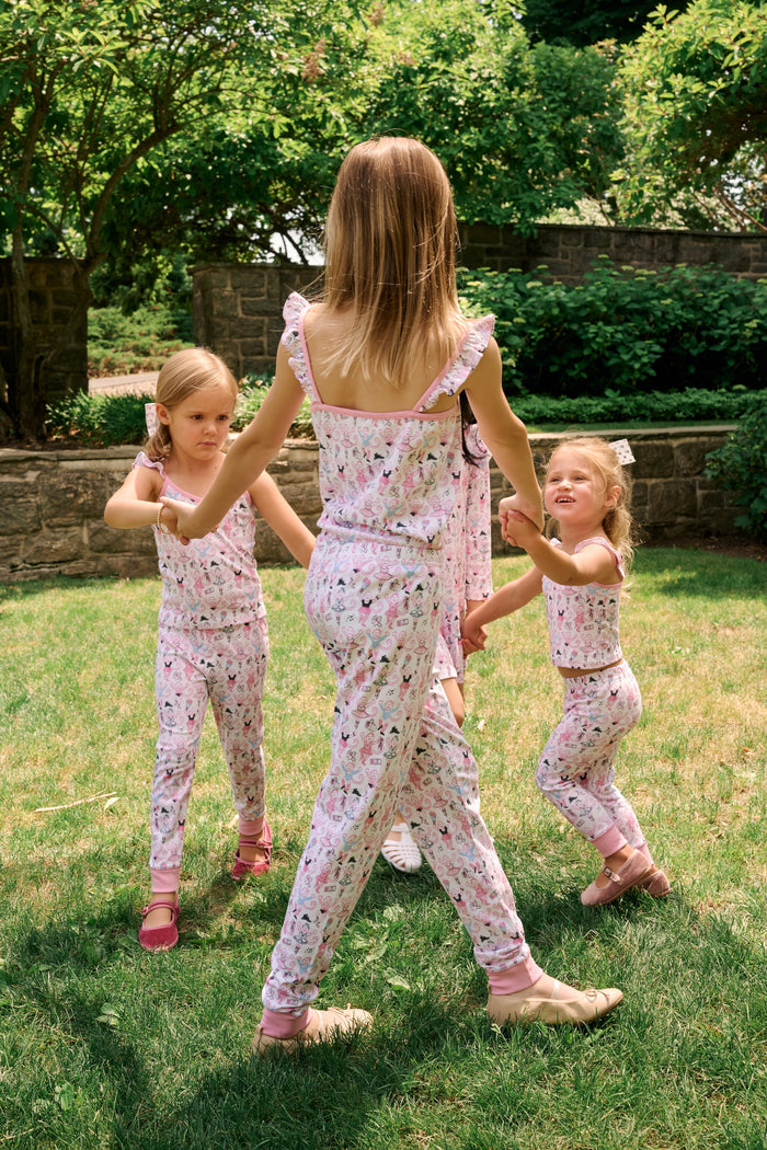 The Kids Monkey Pirouette Blaire Pajamas by Roller Rabbit is a children's pajama set crafted from soft Pima cotton, featuring a sleeveless top with ruffled straps and long pants, both in white with a playful pink, blue, and black monkey cartoon print and pink trim.