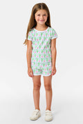 Smiling young girl with long brown hair wearing the Roller Rabbit Kids Monkey Playa Play Set and white shoes, standing against a plain white background.