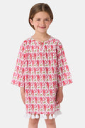 Young girl in a loose Kids Monkey Serafina Tunic by Roller Rabbit—a long-sleeved cotton voile dress with a playful monkey print and white ruffled hem—smiling against a plain white background.