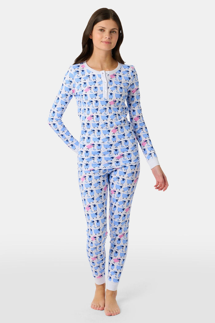 A young boy smiles on a white backdrop, wearing Roller Rabbit's Kids Sammy The Sheep Pajamas—cozy Pima cotton sleepwear featuring a playful sheep print, perfect for sweet dreams.