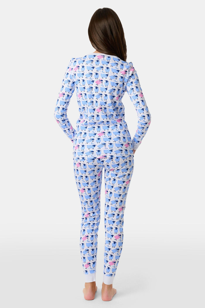 A young boy smiles on a white backdrop, wearing Roller Rabbit's Kids Sammy The Sheep Pajamas—cozy Pima cotton sleepwear featuring a playful sheep print, perfect for sweet dreams.