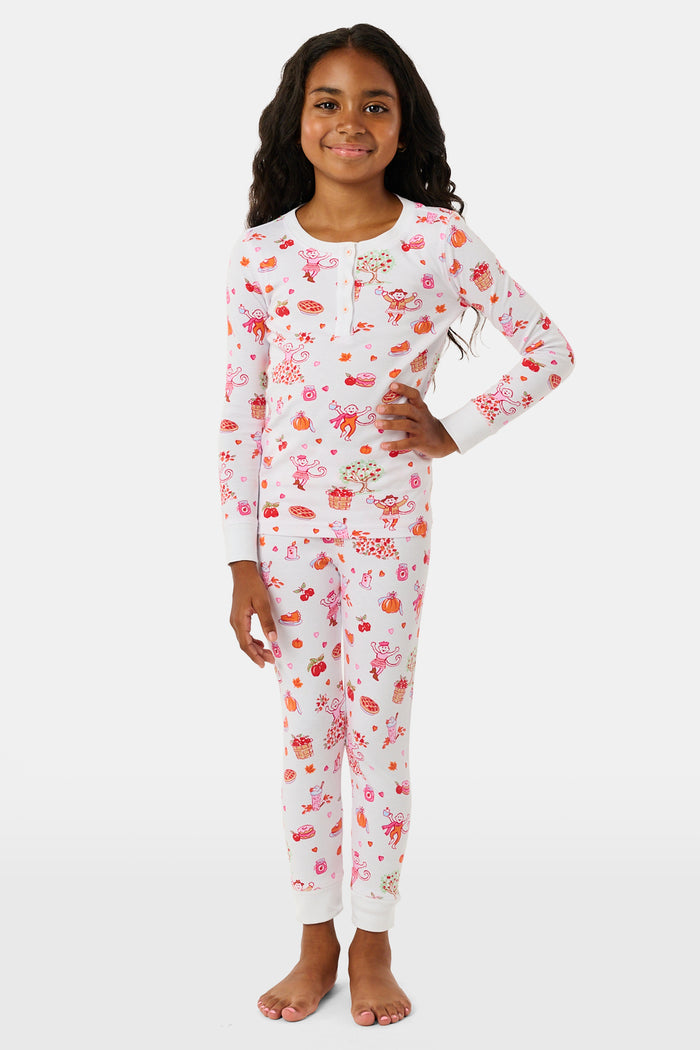 A girl wearing Roller Rabbit Kids Sweater Weather Pajamas stands barefoot, smiling, against a plain white background.