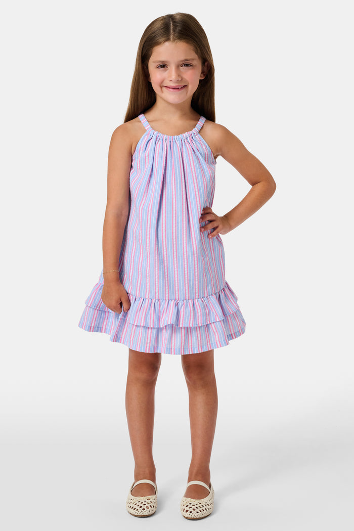 A young girl wearing the Roller Rabbit Kids Sweet Stripe Casey Dress stands in front of lockers, smiling and holding a folder decorated with colorful raindrops.