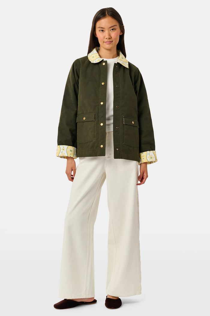 A young girl wearing a Roller Rabbit Kids Lillian Floral Stripe Finn Jacket paired with a matching ruffled skirt and gold ballet flats, standing and smiling against a plain white background—perfect for back-to-school style.
