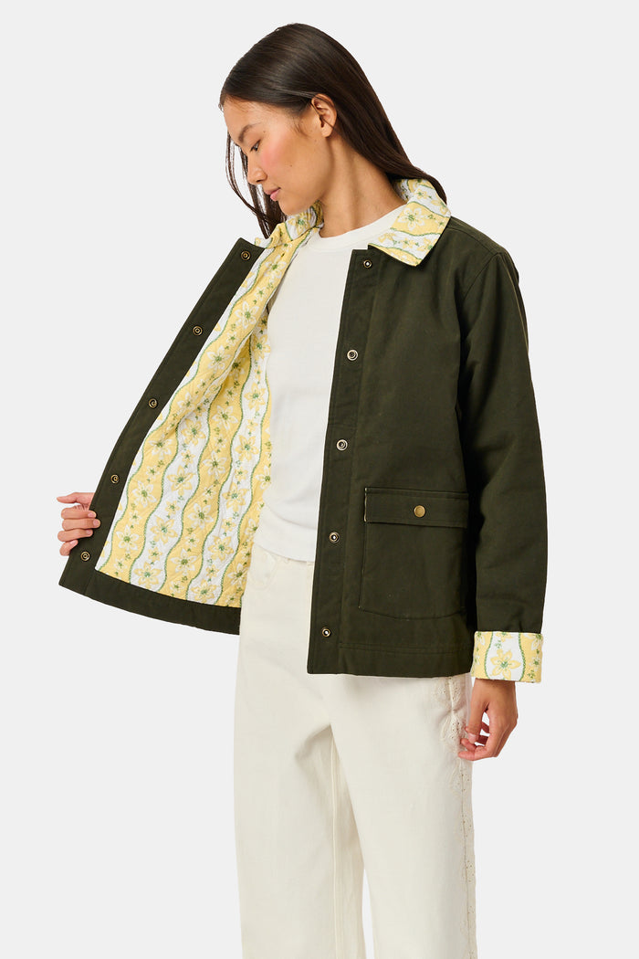 A young girl wearing a Roller Rabbit Kids Lillian Floral Stripe Finn Jacket paired with a matching ruffled skirt and gold ballet flats, standing and smiling against a plain white background—perfect for back-to-school style.