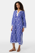 A woman wears the Roller Rabbit Lobster Trellis Johanna Caftan in blue and white, featuring a white V-neckline and hem, paired with sandals against a plain background.