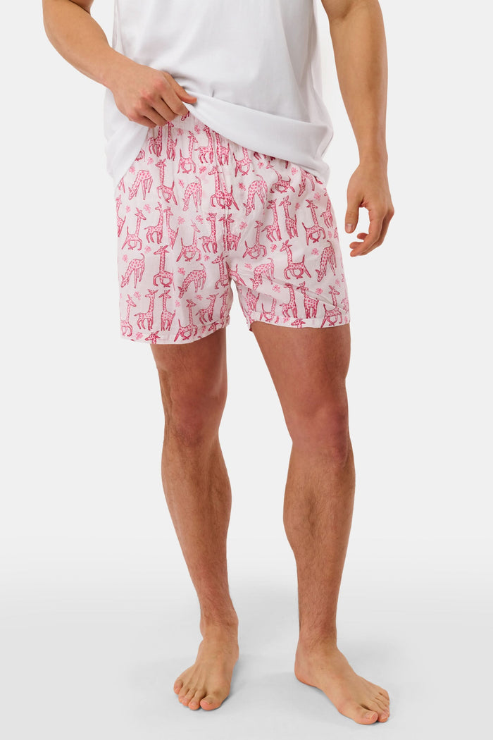 A man stands barefoot in a white T-shirt and Roller Rabbit’s Mens Gigi Giraffe Boxer Set, featuring green giraffe print shorts—ideal for showcasing these stylish cotton boxers as a thoughtful men’s gift.