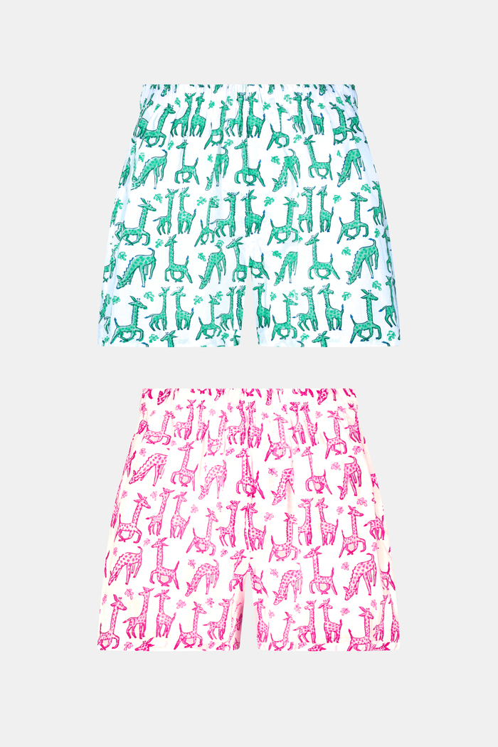A man stands barefoot in a white T-shirt and Roller Rabbit’s Mens Gigi Giraffe Boxer Set, featuring green giraffe print shorts—ideal for showcasing these stylish cotton boxers as a thoughtful men’s gift.
