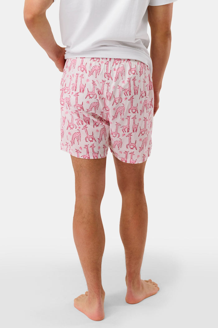 A man stands barefoot in a white T-shirt and Roller Rabbit’s Mens Gigi Giraffe Boxer Set, featuring green giraffe print shorts—ideal for showcasing these stylish cotton boxers as a thoughtful men’s gift.