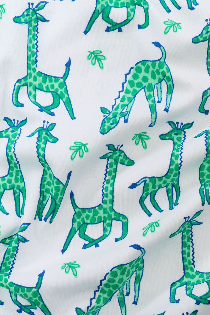 A person wears Roller Rabbit's Mens Gigi Giraffe Simon Pant, white pajama pants with a giraffe print, standing barefoot against a plain white background. Made from 100 Pima Cotton, the pull-on style features a hand in the pocket and a partially visible upper body.