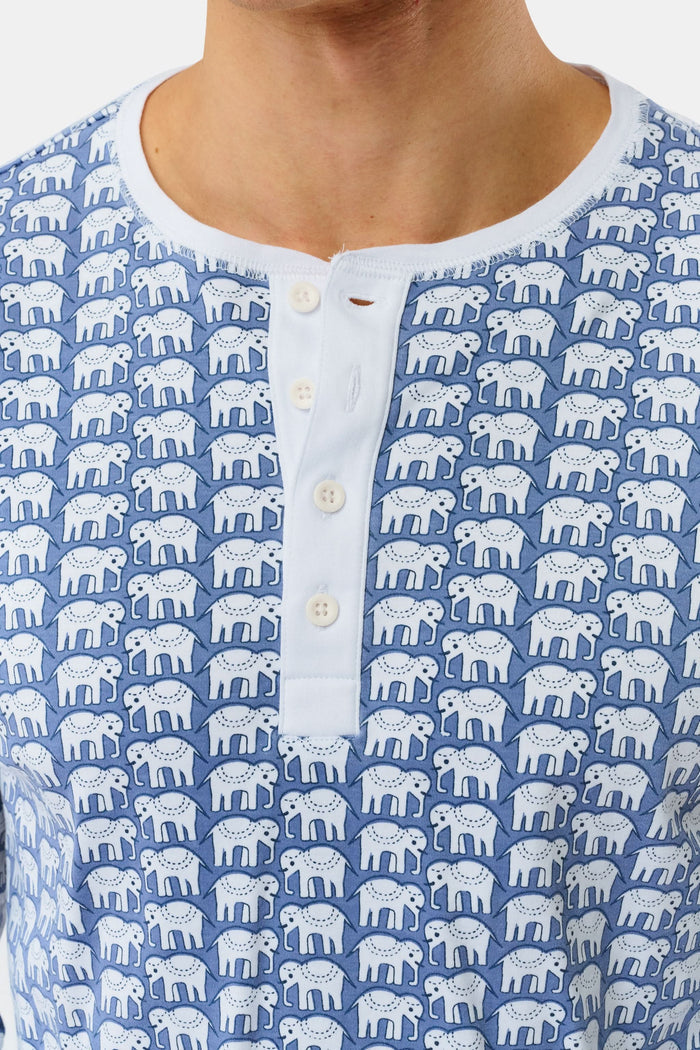 A man stands barefoot in Roller Rabbit's Mens Hathi Spencer Pajamas, a blue and white long-sleeve set with a small pattern and buttoned collar, made from 100 Pima Cotton, against a plain white background.