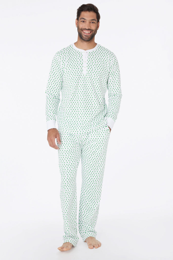 A man stands barefoot and smiling in Roller Rabbit Mens Hearts Spencer Pajamas with an Emerald Hearts print, long sleeves, and 100 Pima cotton, against a plain white background.