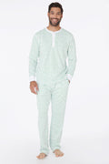 A man stands barefoot and smiling in Roller Rabbit Mens Hearts Spencer Pajamas with an Emerald Hearts print, long sleeves, and 100 Pima cotton, against a plain white background.