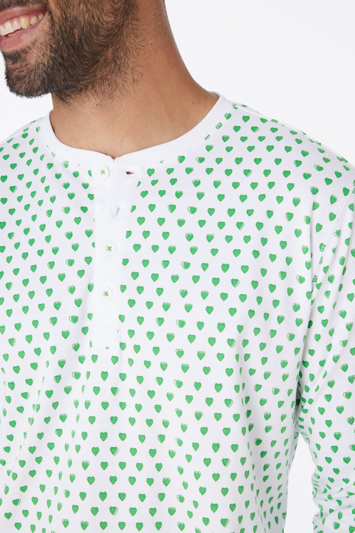 A man stands barefoot and smiling in Roller Rabbit Mens Hearts Spencer Pajamas with an Emerald Hearts print, long sleeves, and 100 Pima cotton, against a plain white background.