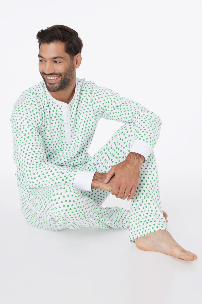 A man stands barefoot and smiling in Roller Rabbit Mens Hearts Spencer Pajamas with an Emerald Hearts print, long sleeves, and 100 Pima cotton, against a plain white background.