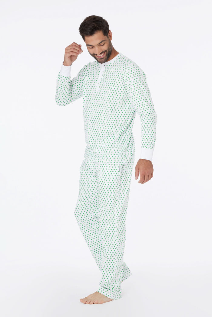 A man stands barefoot and smiling in Roller Rabbit Mens Hearts Spencer Pajamas with an Emerald Hearts print, long sleeves, and 100 Pima cotton, against a plain white background.