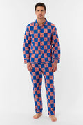A man with short brown hair and a neutral expression stands barefoot against a white background, wearing the Roller Rabbit Mens Moby Grand Prix Loungewear set in blue and pink checkered cotton with long sleeves and pants.