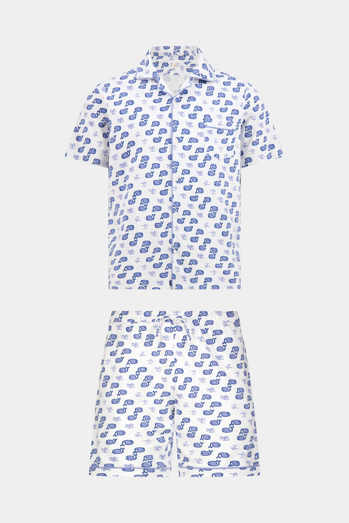 A man stands barefoot facing forward in Roller Rabbit’s Mens Moby Louie Pajamas—a Pima cotton set with blue patterns on white, featuring a short-sleeve button-up shirt and shorts—against a plain white background.