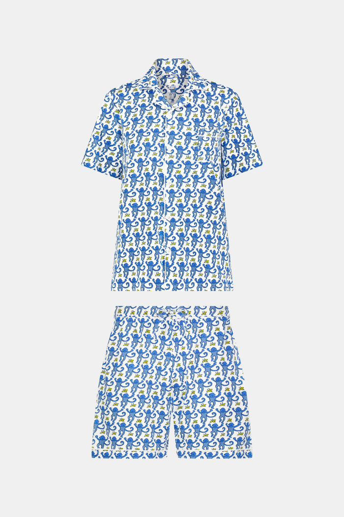A man stands barefoot against a white background wearing Roller Rabbit Mens Monkey Louie Pajamas—a matching short-sleeve button-up shirt and shorts featuring a blue and white abstract print in 100 Pima cotton.