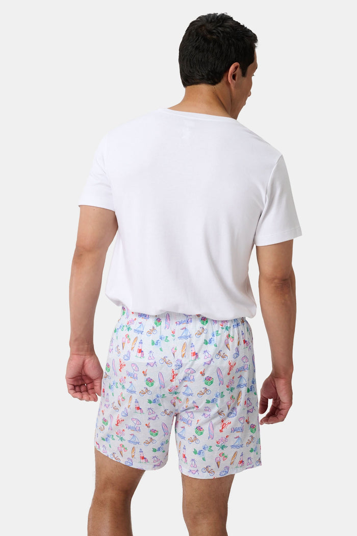 The Roller Rabbit Mens Summer Club/Clementine Trellis Boxer Set includes two soft cotton boxers: one with an orange fruit and branch print, the other with a vibrant beach scene featuring crabs, shells, and sandcastles for all-day comfort.
