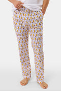 A man with short dark hair stands barefoot against a plain background, wearing a white t-shirt and Roller Rabbit Mens Tigers Lovely Monkey Simon Pant lounge pants with a yellow and brown design. He has a relaxed, neutral expression.