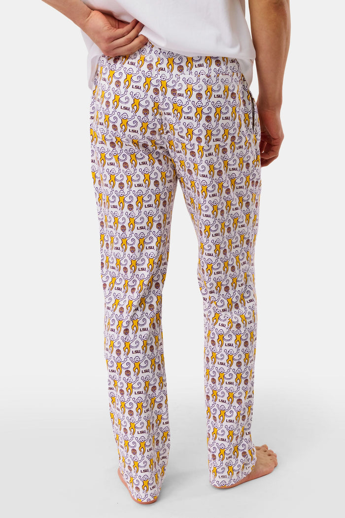 A man with short dark hair stands barefoot against a plain background, wearing a white t-shirt and Roller Rabbit Mens Tigers Lovely Monkey Simon Pant lounge pants with a yellow and brown design. He has a relaxed, neutral expression.