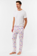 A man stands barefoot against a plain background, wearing the Roller Rabbit Mens Tinned or Twist Milo Set—a Pima cotton T-shirt paired with colorful drawstring waist pants featuring cartoon food patterns.