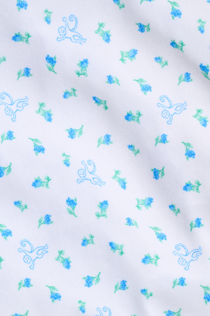 Introducing the Mini Monkey Blossom Bea Sweatpants from Roller Rabbit—white pajama pants featuring a blue and green Mini Monkey Blossom floral print, an elastic waistband, and "Sleep Club" text in blue on the left hip. These cozy sweatpants offer a relaxed, comfortable fit.