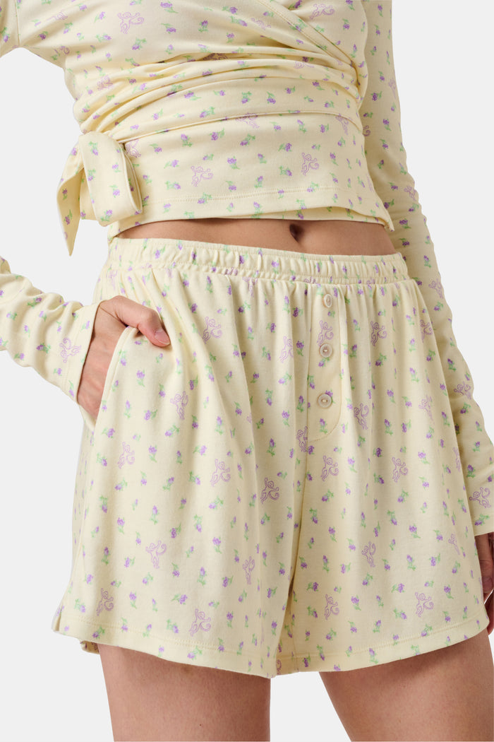 The Mini Monkey Blossom Brooklyn Boxer by Roller Rabbit features light yellow Pima cotton with a delicate pastel floral print and an elastic waistband. Displayed on a plain white background, these comfortable women’s loungewear sleep shorts are perfect for relaxing at home.