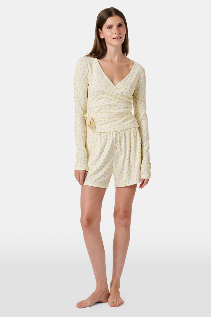 The Mini Monkey Blossom Brooklyn Boxer by Roller Rabbit features light yellow Pima cotton with a delicate pastel floral print and an elastic waistband. Displayed on a plain white background, these comfortable women’s loungewear sleep shorts are perfect for relaxing at home.