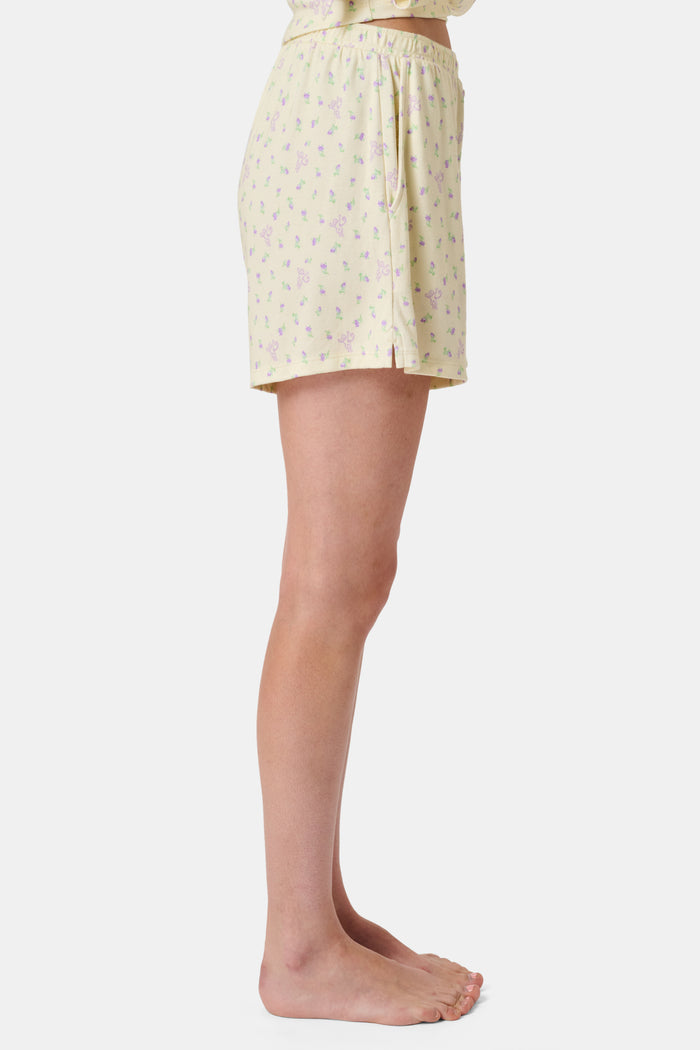 The Mini Monkey Blossom Brooklyn Boxer by Roller Rabbit features light yellow Pima cotton with a delicate pastel floral print and an elastic waistband. Displayed on a plain white background, these comfortable women’s loungewear sleep shorts are perfect for relaxing at home.