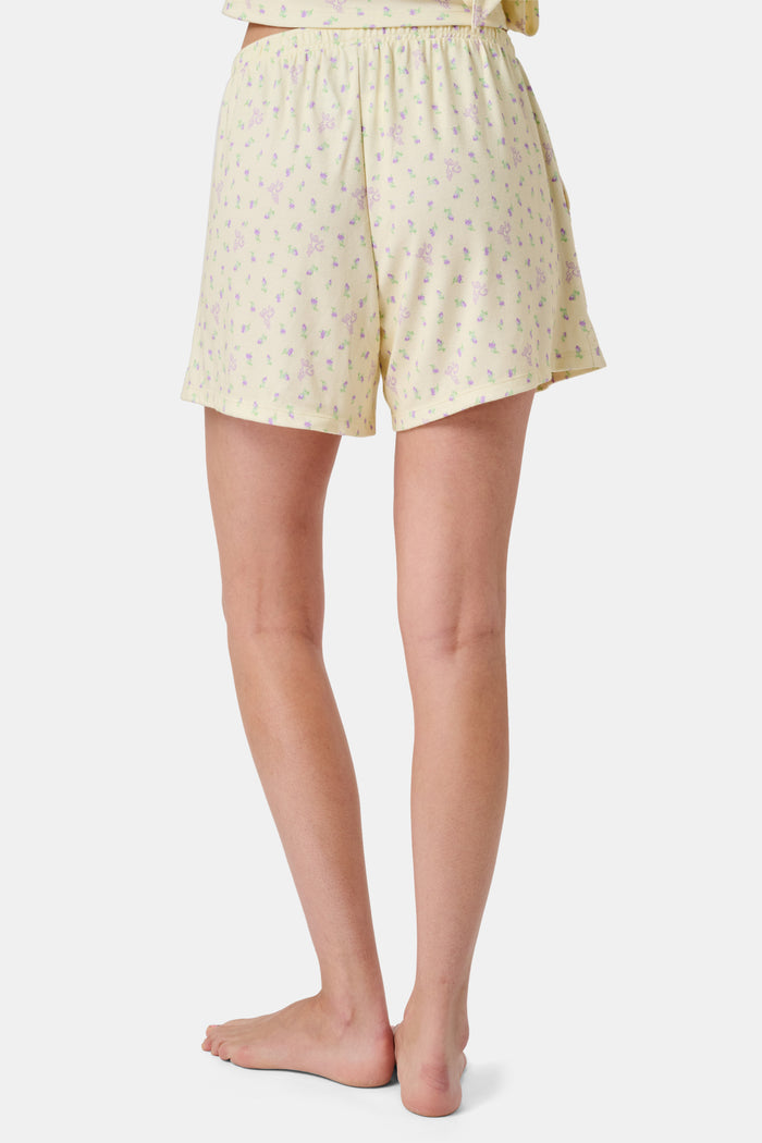 The Mini Monkey Blossom Brooklyn Boxer by Roller Rabbit features light yellow Pima cotton with a delicate pastel floral print and an elastic waistband. Displayed on a plain white background, these comfortable women’s loungewear sleep shorts are perfect for relaxing at home.